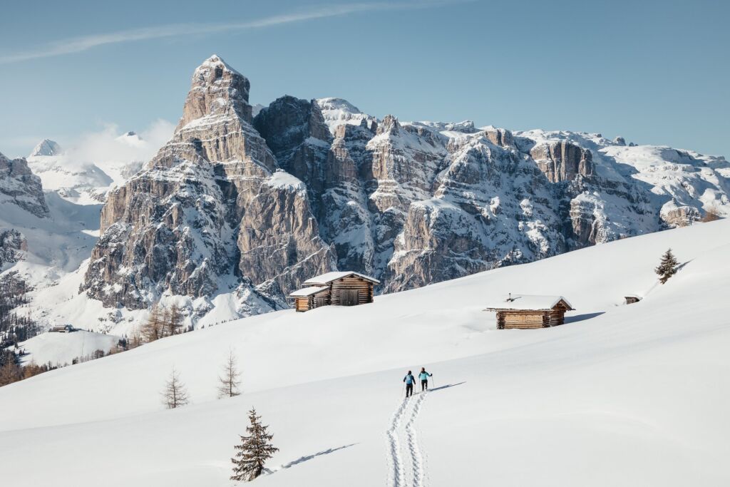 A couple walking towards a hut on the snow capped mountains