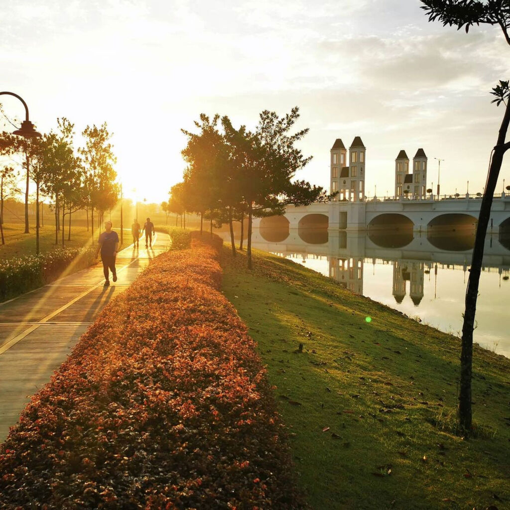 People walking by the lake in Dragonfly Park as the sun is setting 