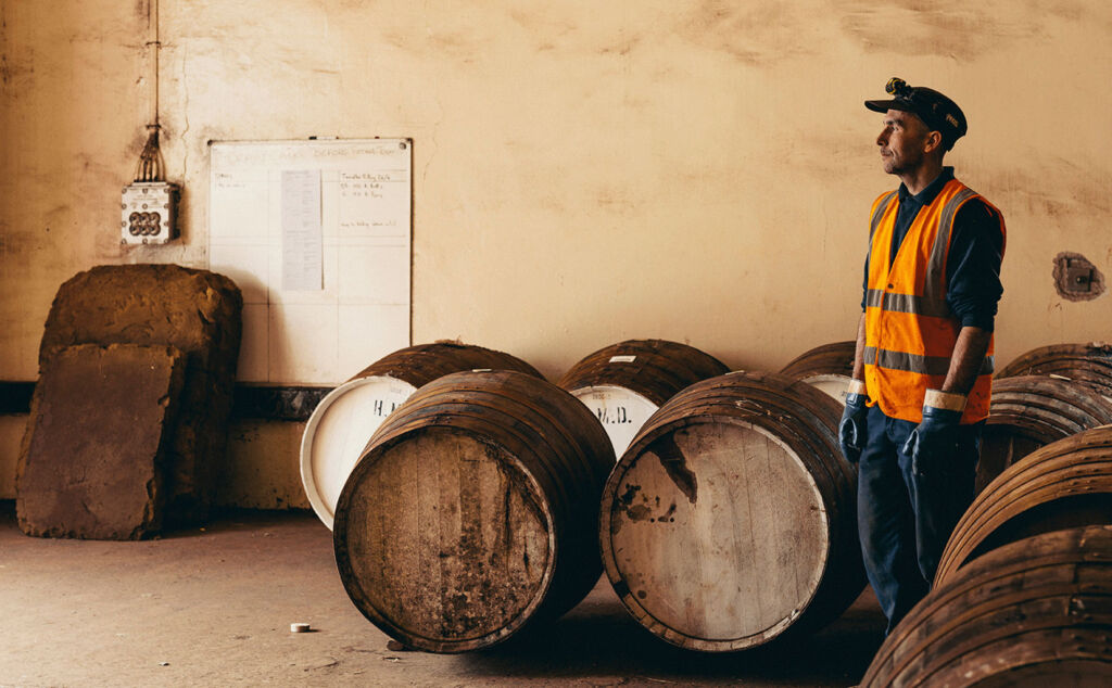 A male member of staff working with barrels in the distillery
