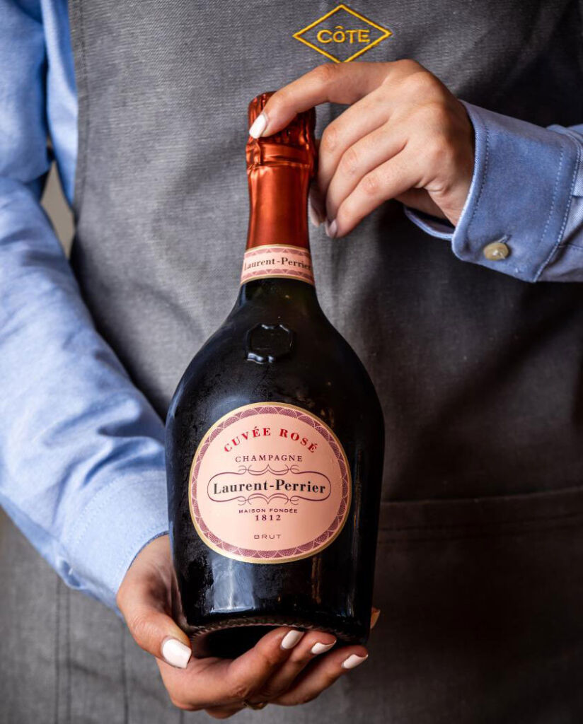 A member of the restaurant team holding a bottle of Laurent-Perrier Champagne