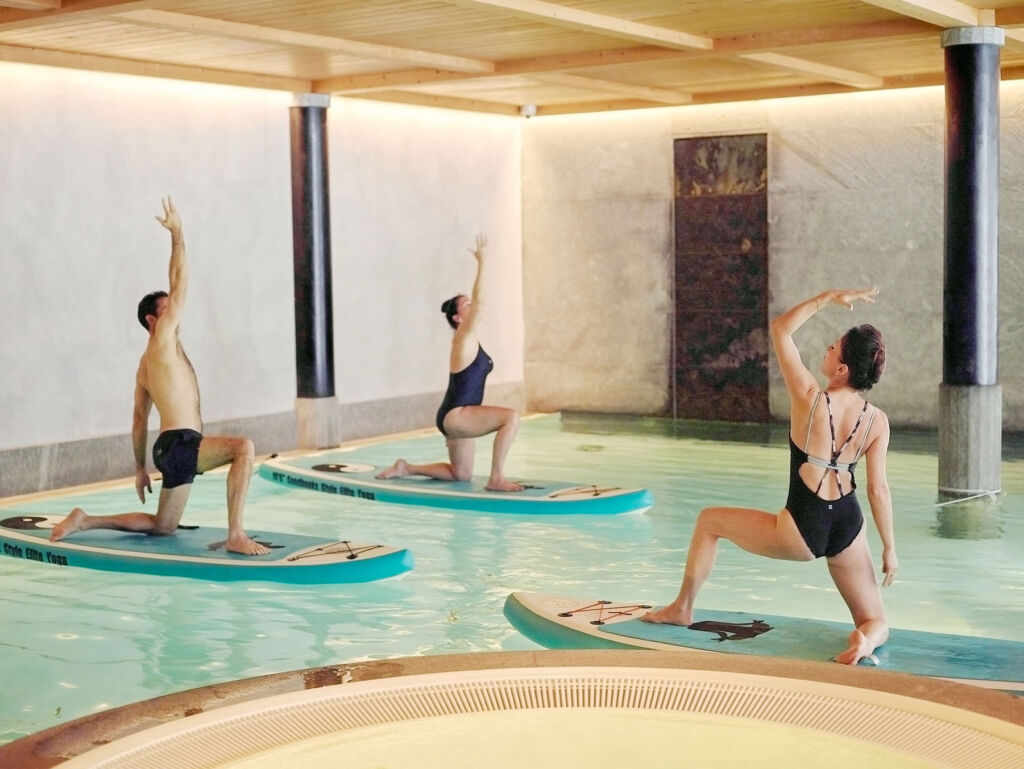 Guests doing yoga on the stand up paddle boards on the indoor pool