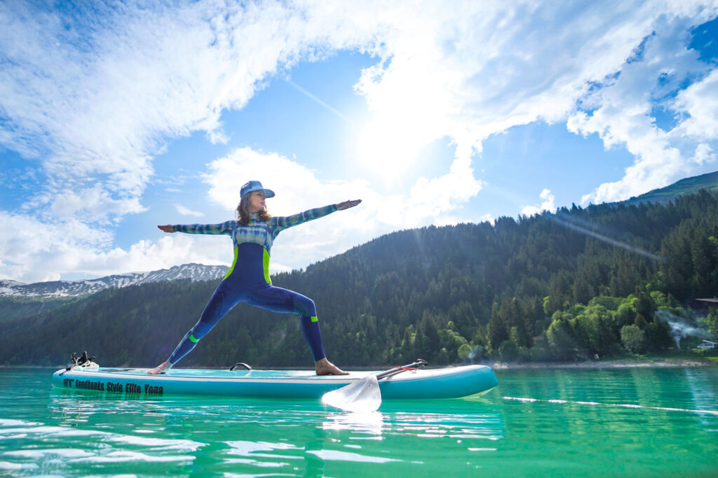 A young woman doing yoga on a board on the lake