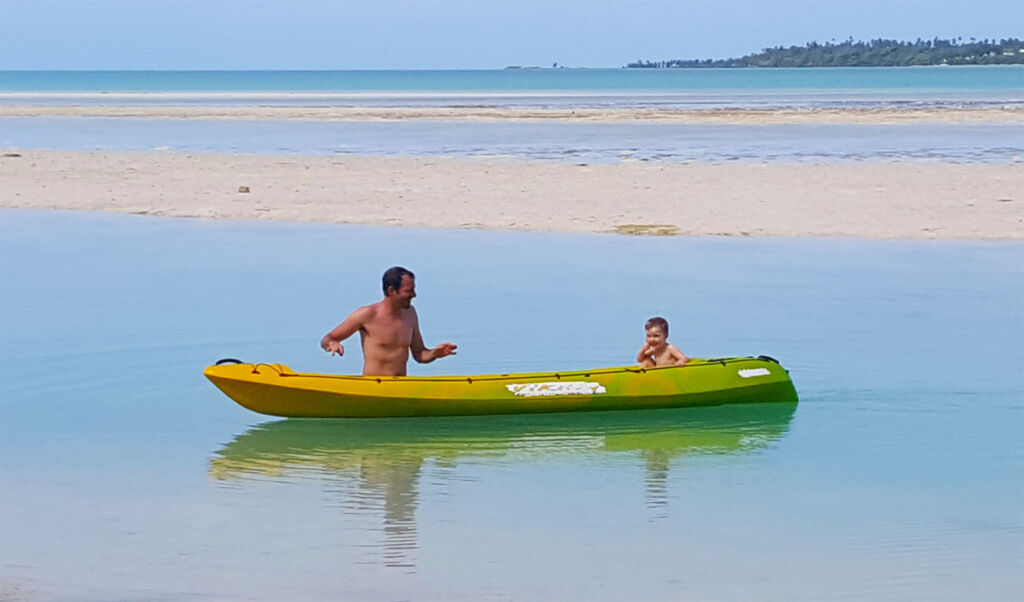 A father and son enjoying a kayak ride in the shallow water