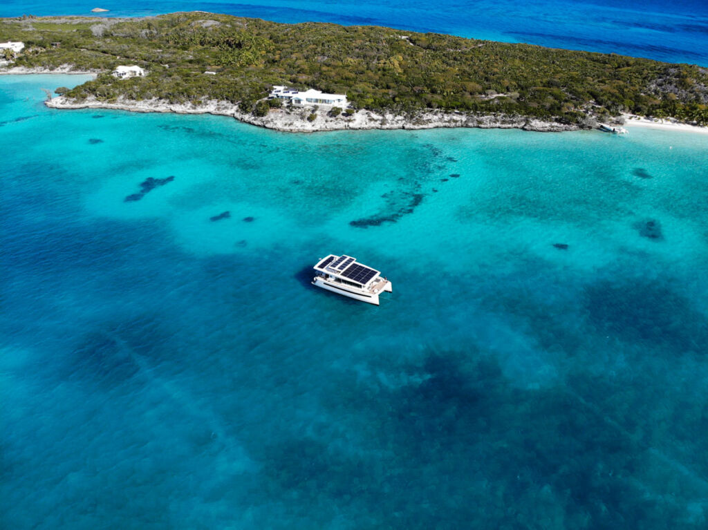 An aerial view of a solar powered yacht sailing past an island in the Bahamas