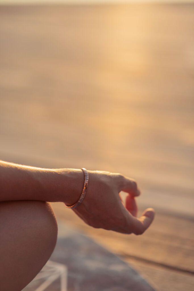 A woman touching her index finger to her thumb on the beach