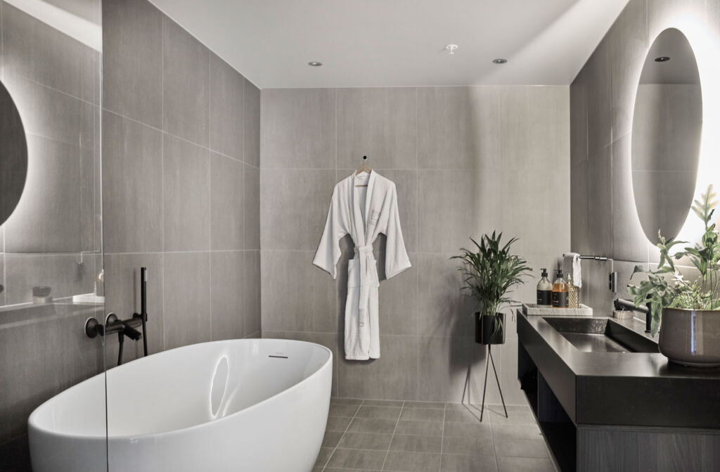 A look inside one of the bathrooms with a freestanding tub and thick dressing gown hanging on the wall