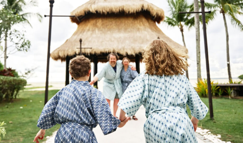 Children running towards their parents, all wearing the sustainable robes