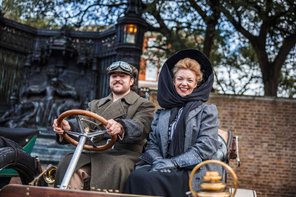 A couple in period costume driving a beautiful classic