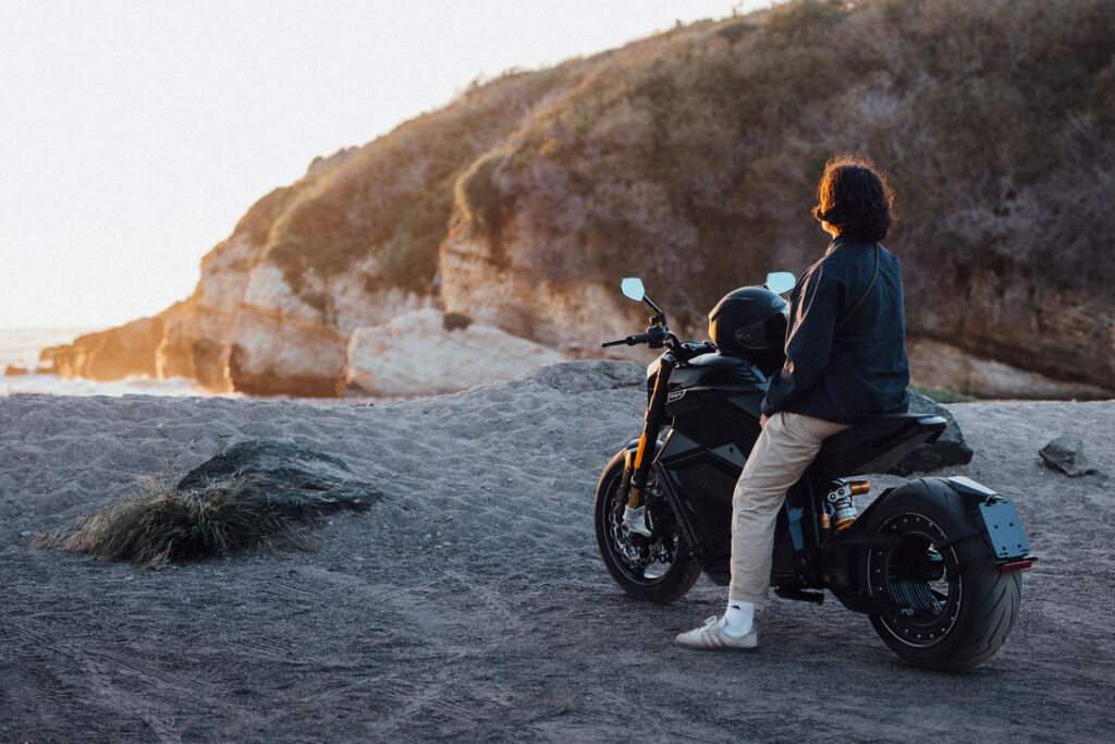 A woman sat on a bike at the beach watching the sunset