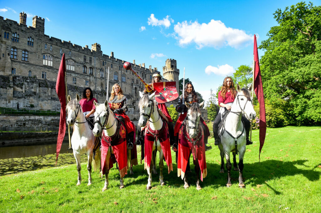 The lead female jousters on horseback in front of the castle