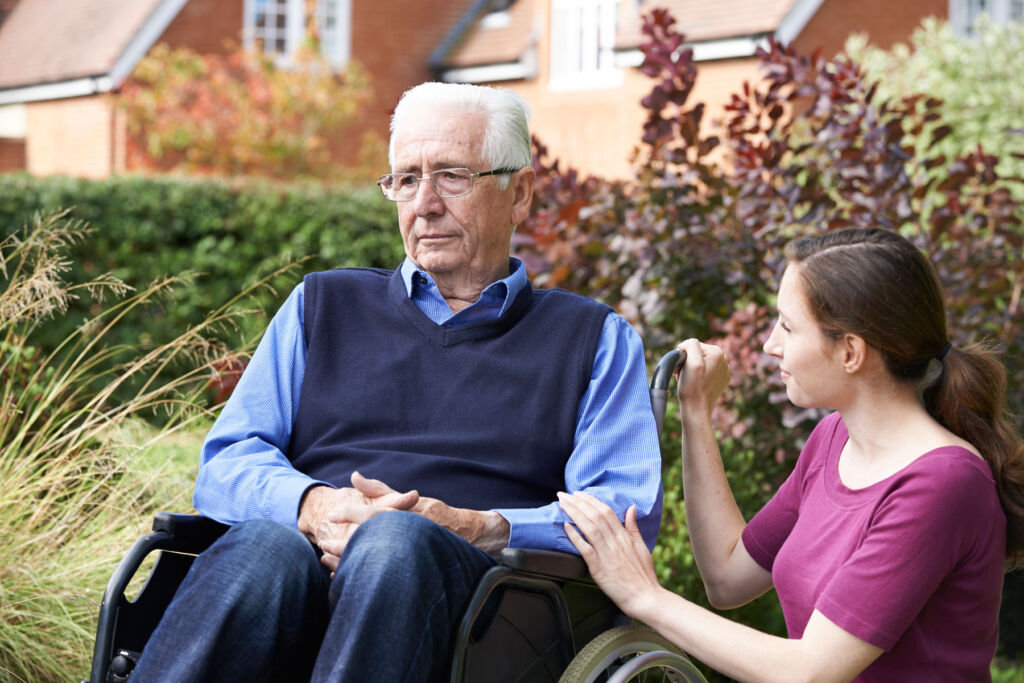 A care talking to an older man in a garden