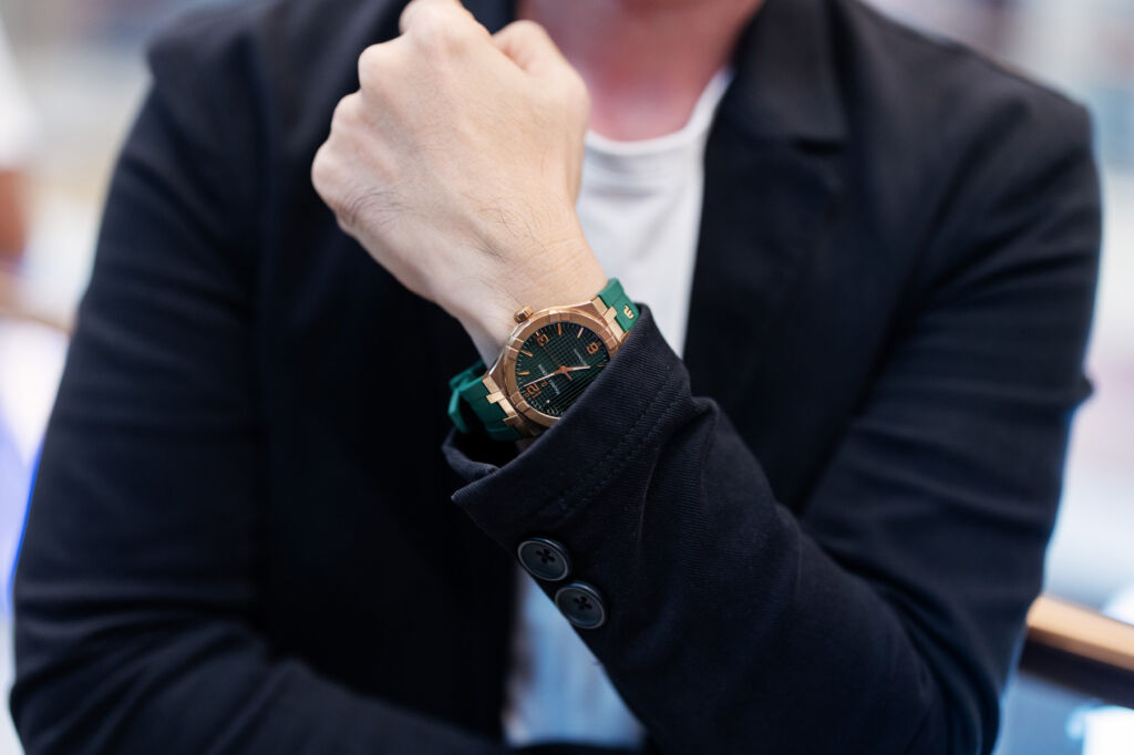 A man wearing a gold AIKON with a green strap