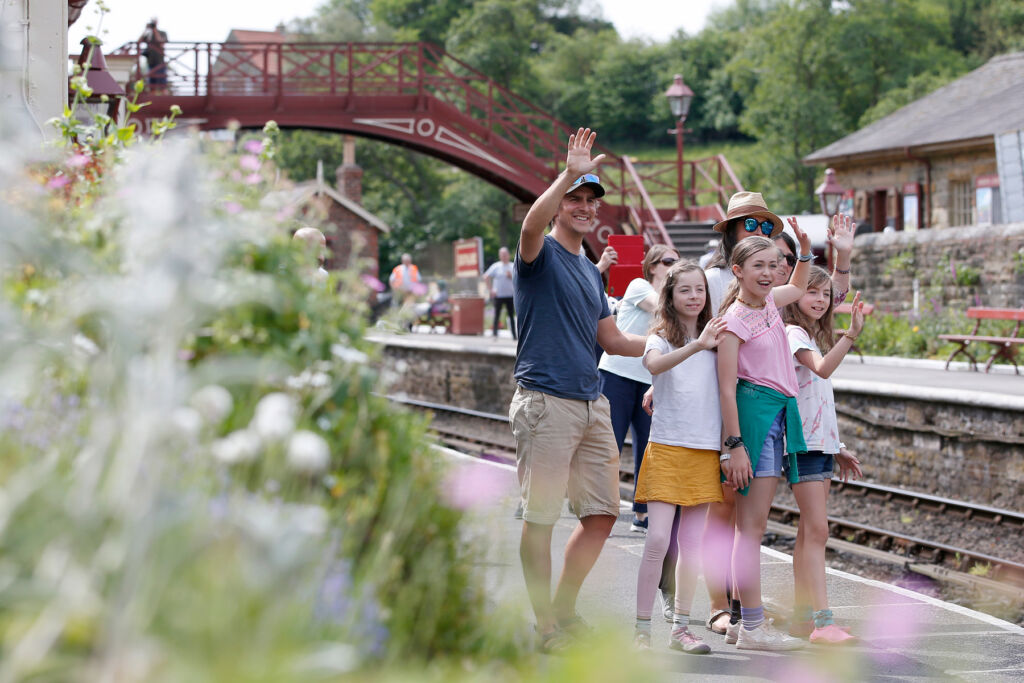 A family on the platform waving to train passengers