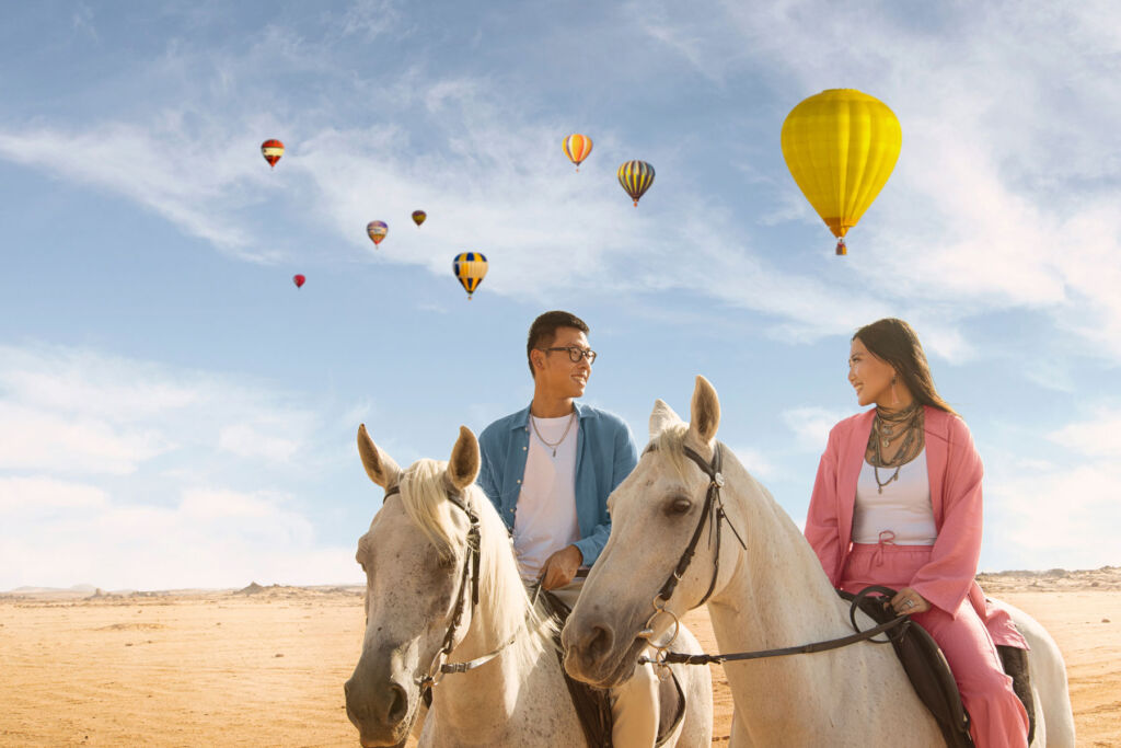 An image showing young Indonesian's riding white horses in the desert