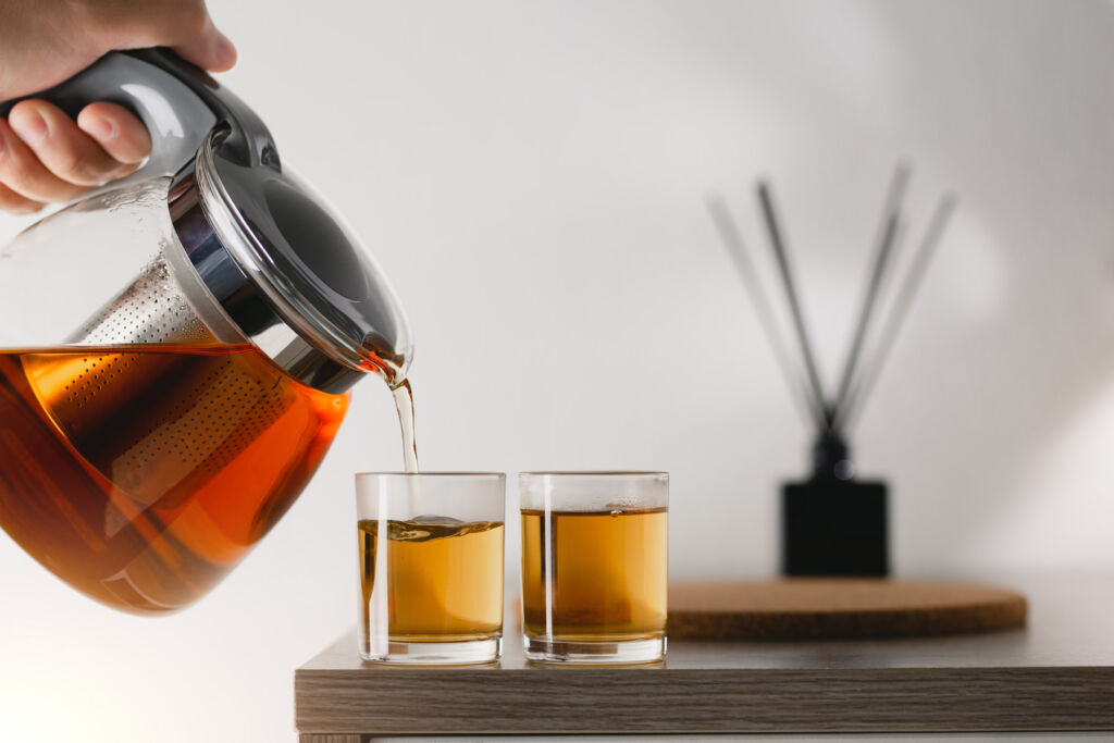 Two glasses being filled with freshly brewed tea