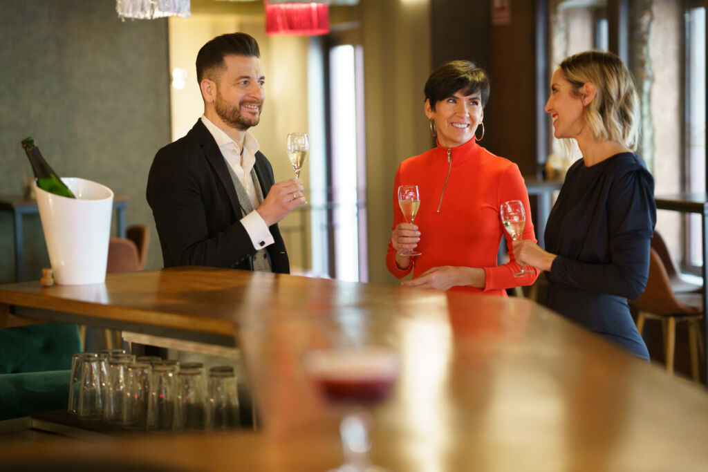 A man and two women trying some sparkling wine at a bar
