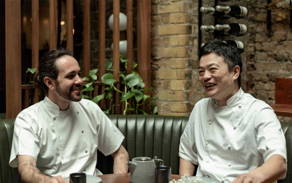 The two chefs sharing a laugh at a table