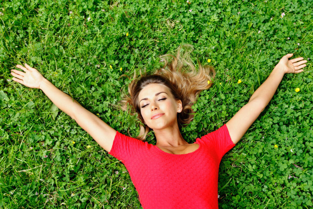 A woman enjoying the sun while laying on the grass