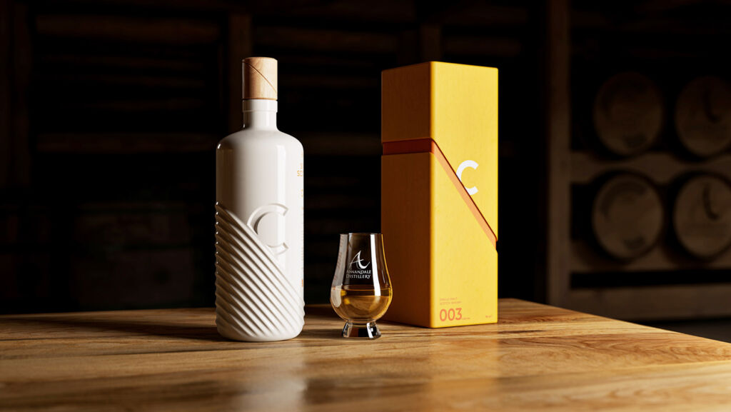 The uniquely designed bottle placed next to its box and a glass of the whisky