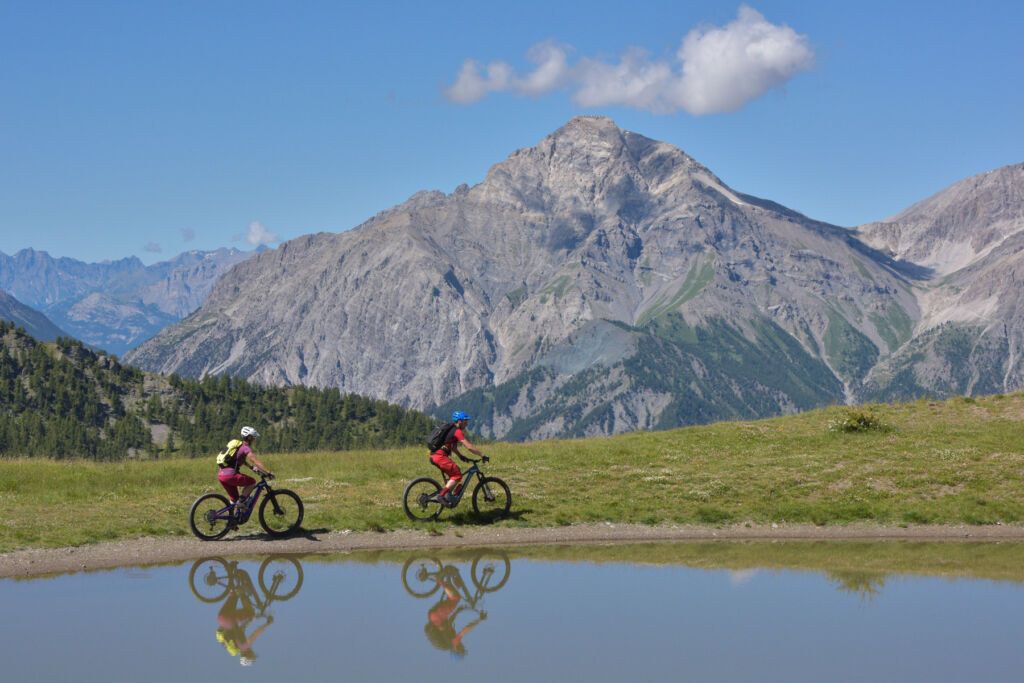 A couple enjoying a leisurely bicycle ride next to a mountain lake