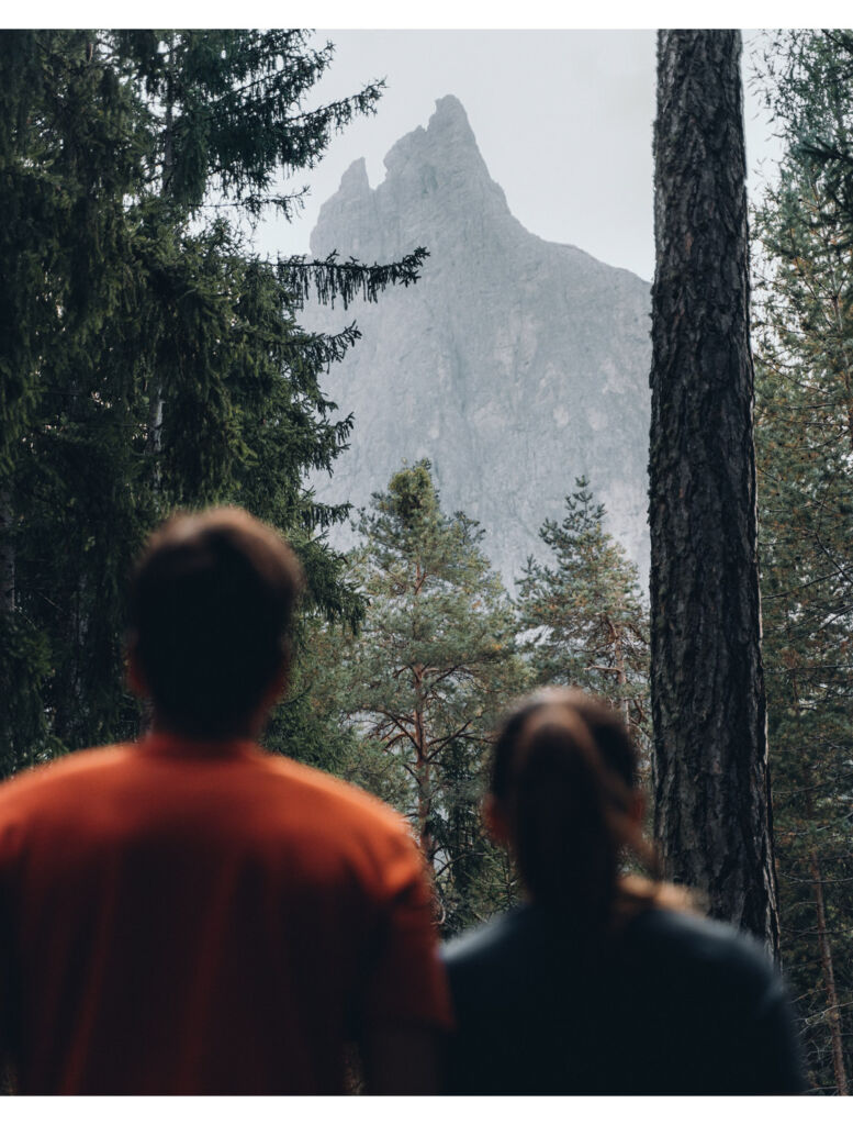 A couple looking at a mountain peak from the forest