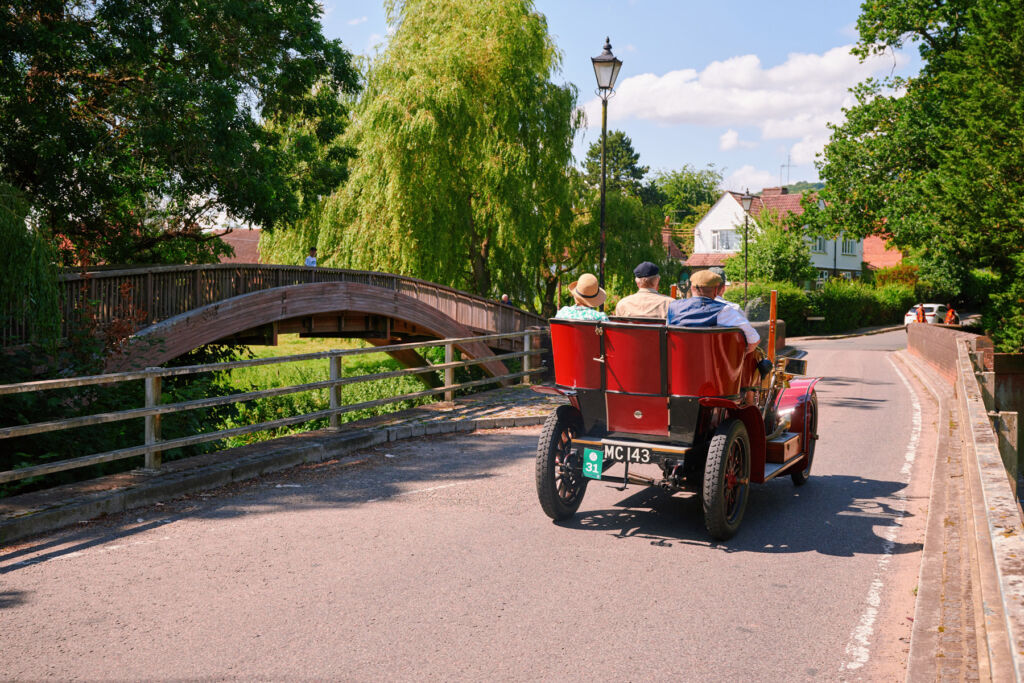 A photograph showing the rear of a red car driving over a bridge