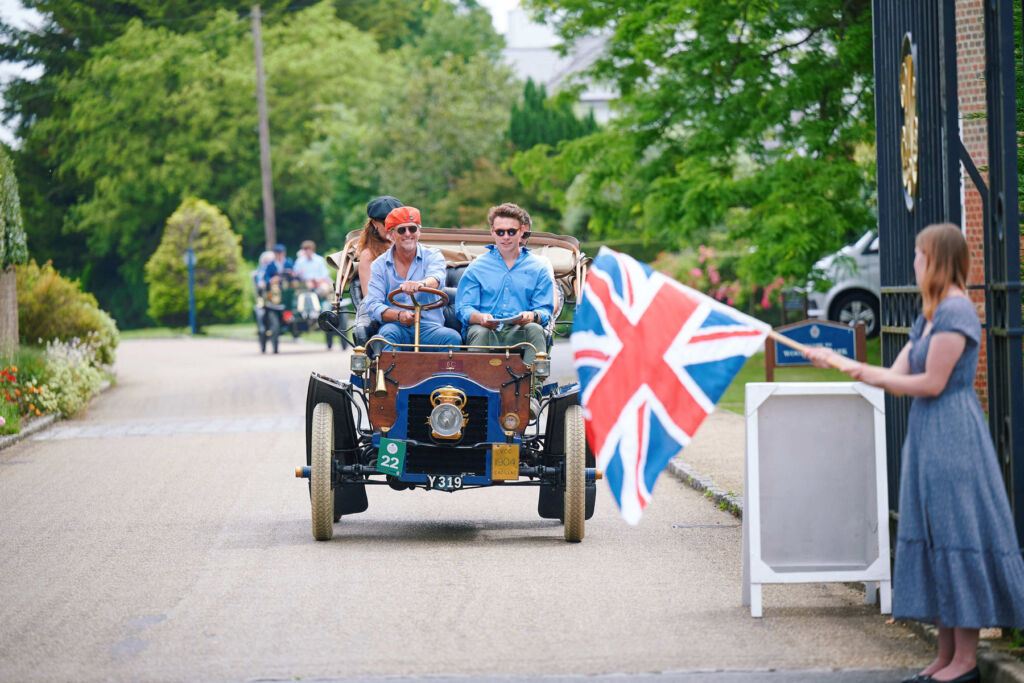 One of the cars leaving the gates with a young spectator waving the Union Jack flag