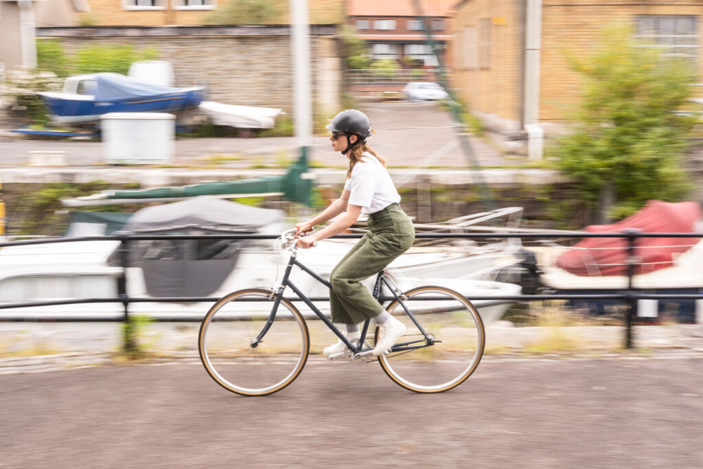 A photograph showing a woman cycling by the side of a canal wearing the new helmet