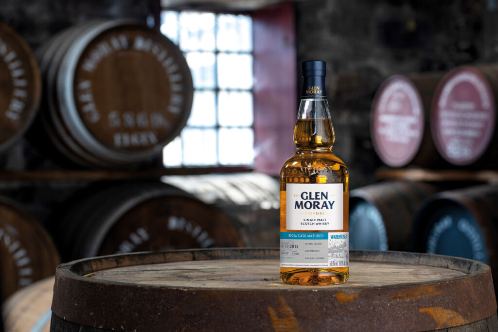 A bottle of the Glen Moray placed on top of a barrel in the distillery cellar