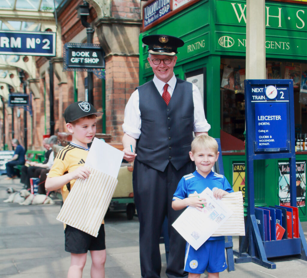 Two young boys showing their activity packs to the station master