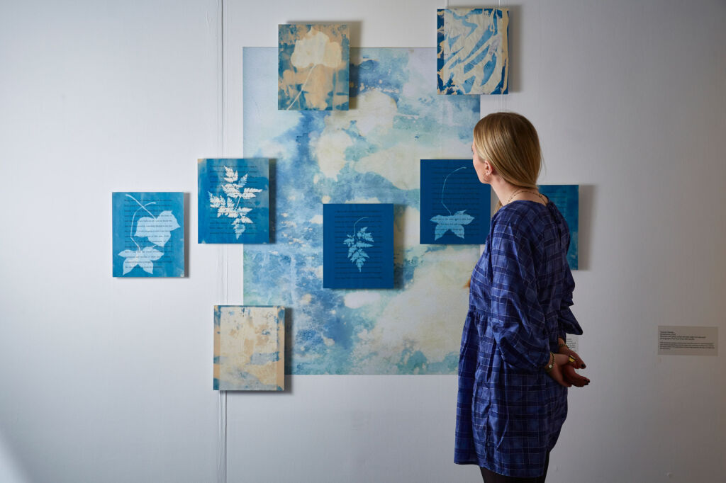 A woman admiring a series of artworks on a wall