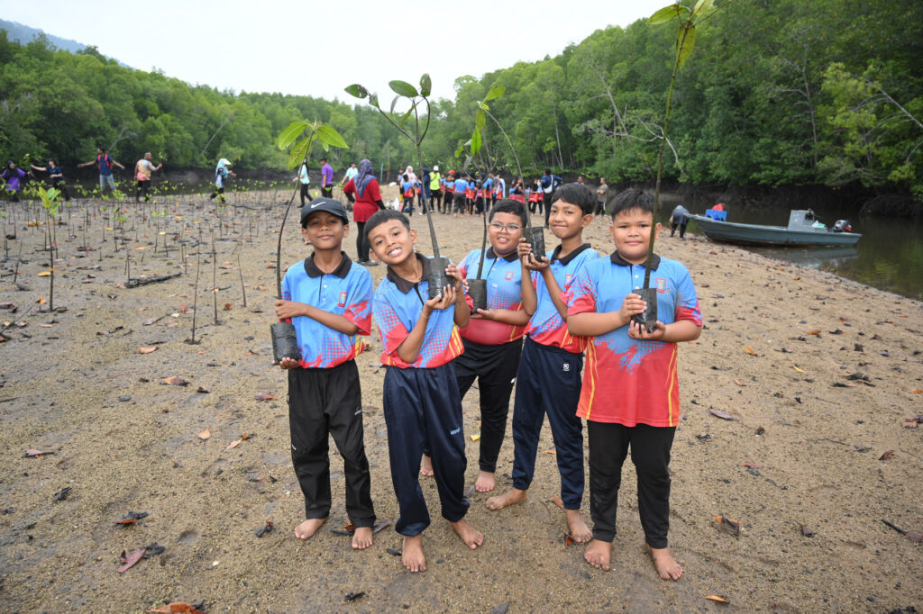 Five young boys holding trees ready for to be planted