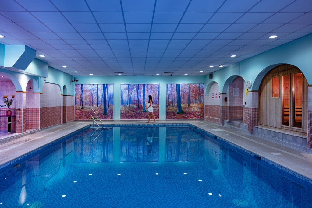 A female guest walking around the indoor swimming pool