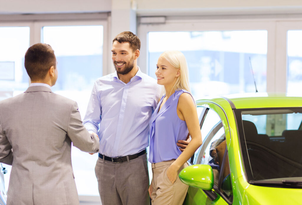 A couple talking to a car salesman in a showroom