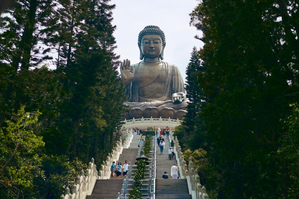 People walking up the steps to the stone Buddha statue