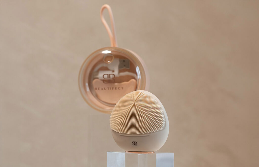 The cleansing device on a pedestal in front of its rose coloured case