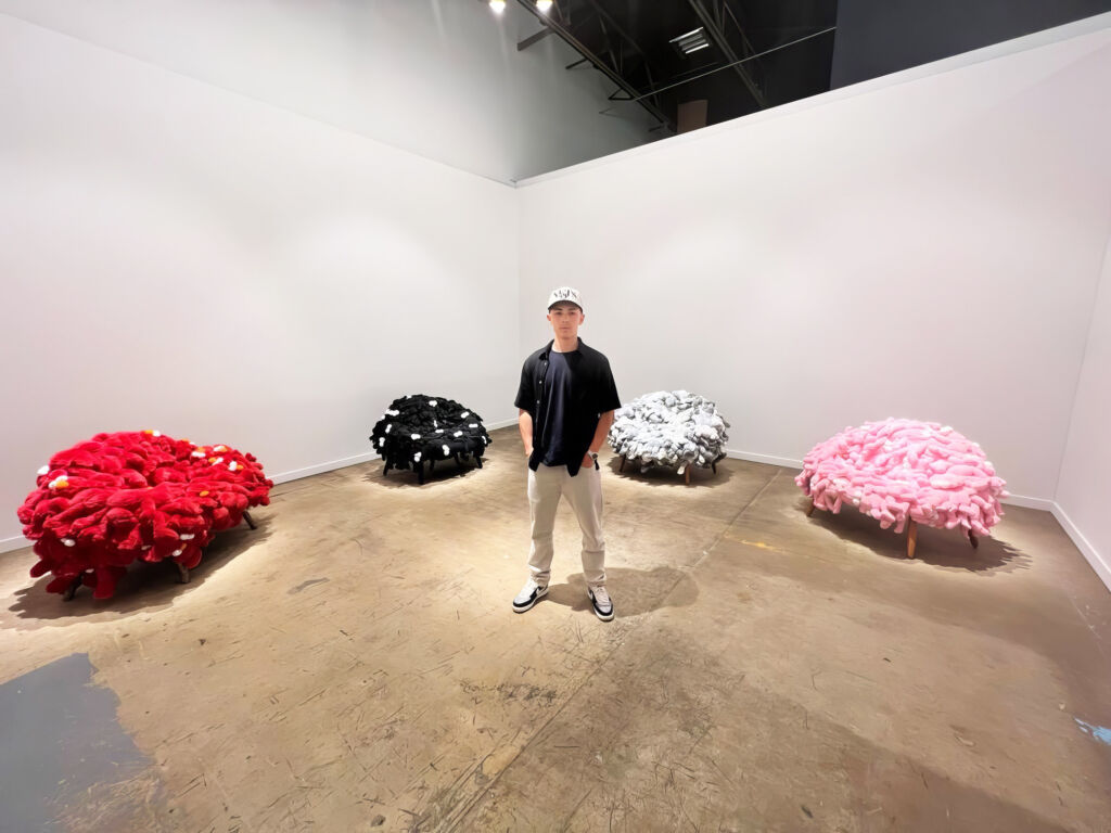 A young man standing in a room with four pieces of contemporary art