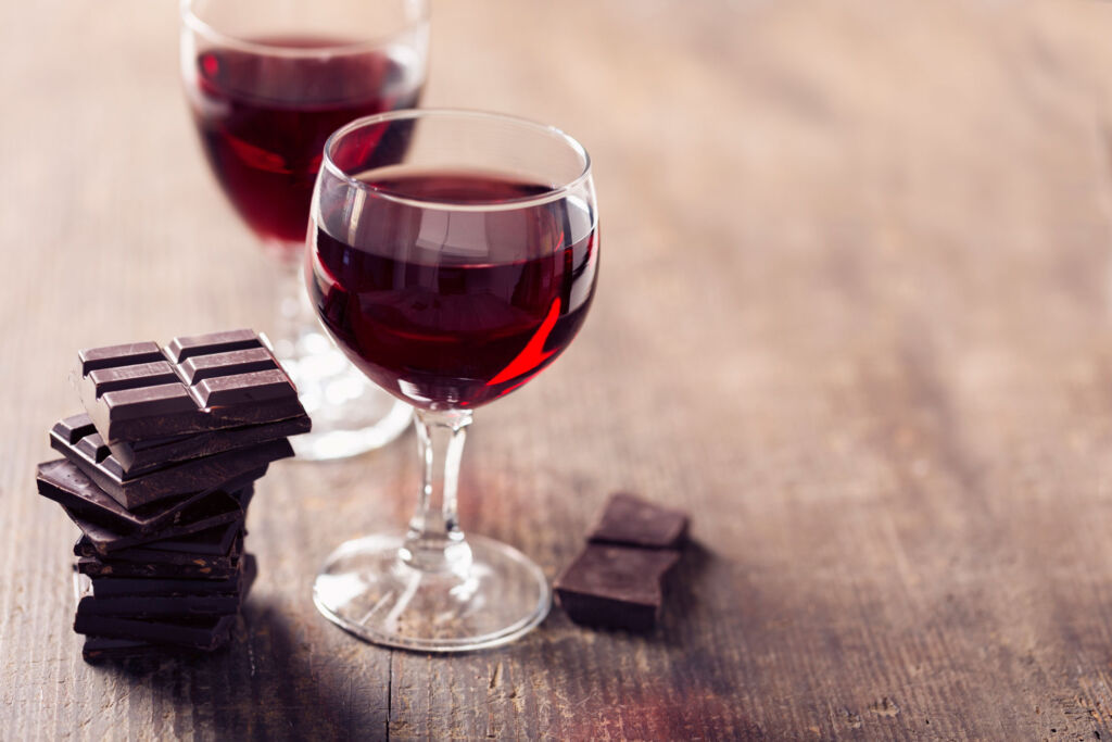 Two glasses of red wine next to pieces of dark chocolate