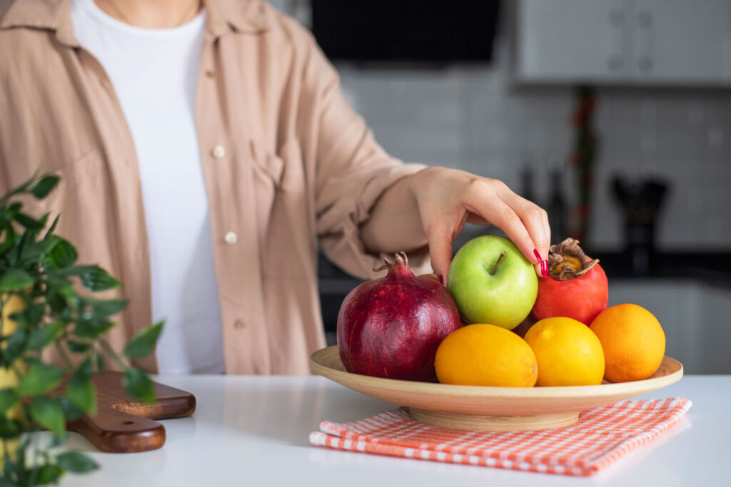 A woman reaching for a piece of fruit