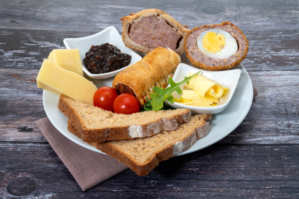 A plate with scotch eggs chesses sausage rolls and more