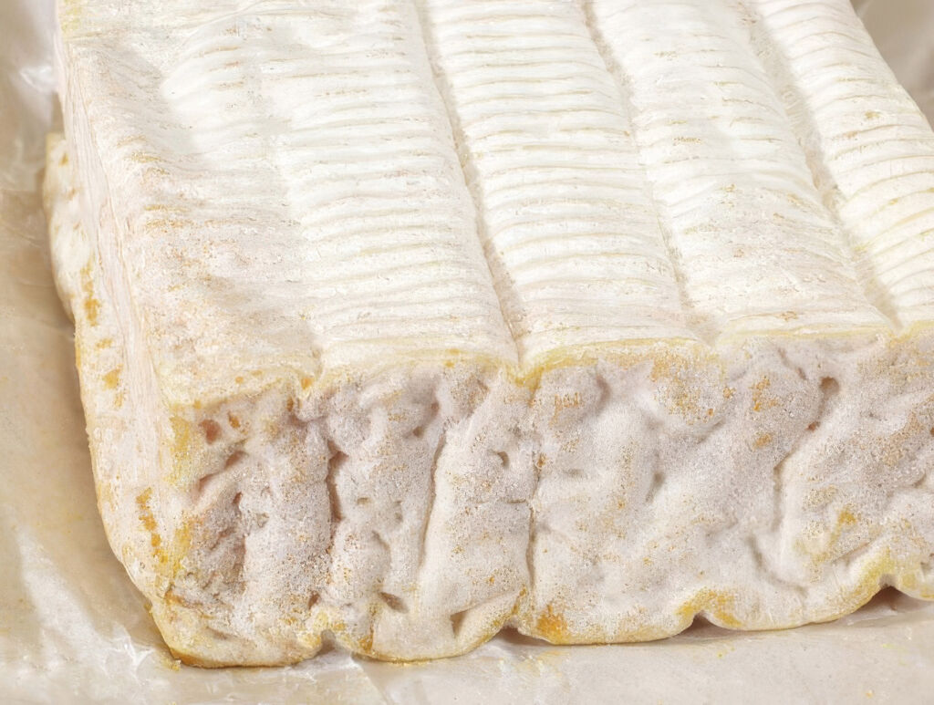 A close up view of a piece of Pont-l'Evêque PDO cheese