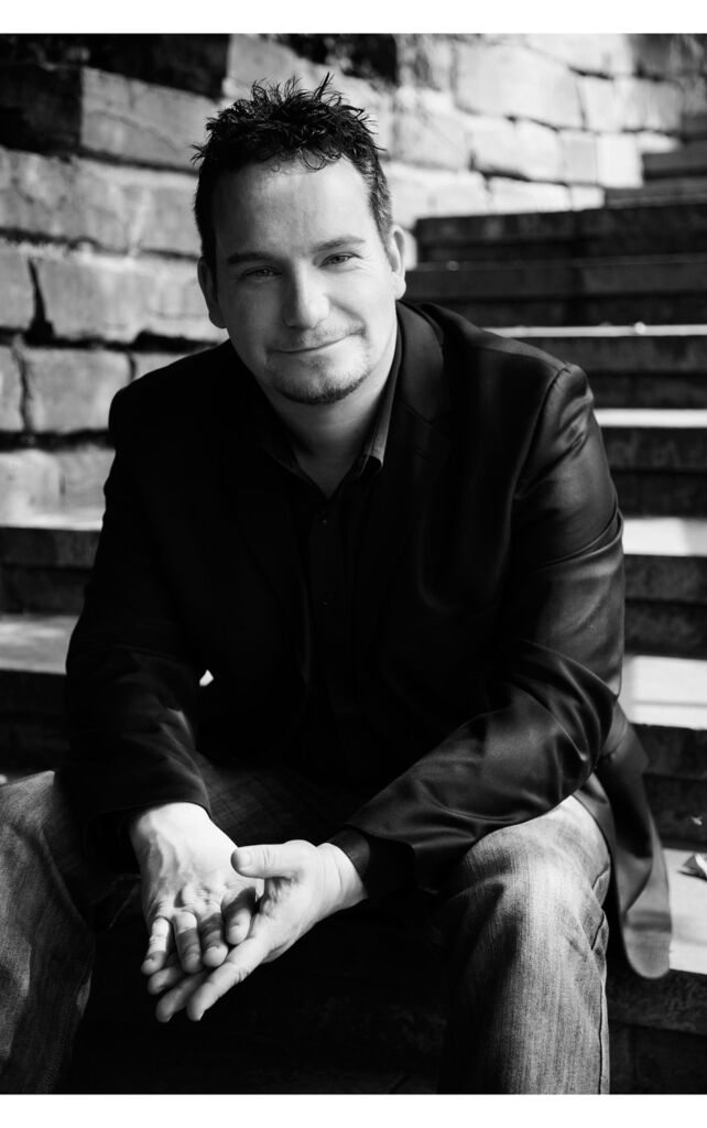 A black and white photograph of the author sitting on some steps