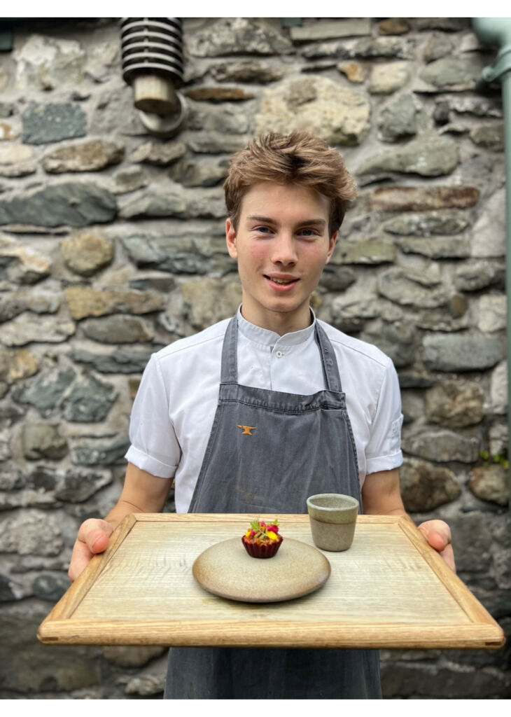 A young chef carrying a dish on a tray