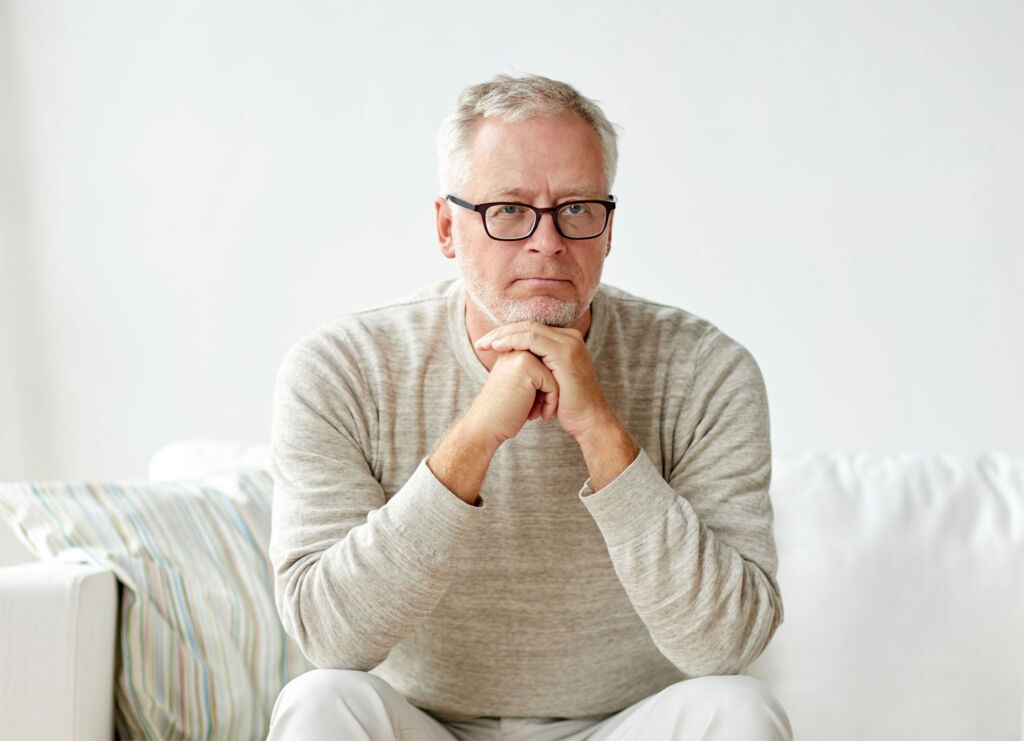 A man deep in thought sitting on a sofa