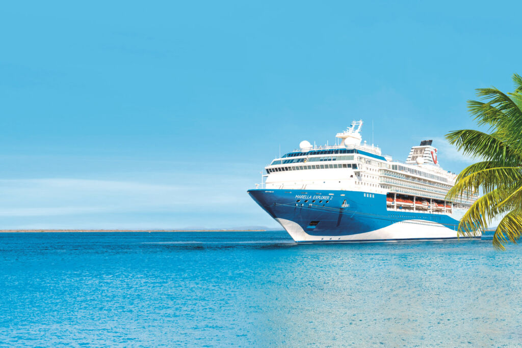 A Marella cruise ship passing by a tropical coast