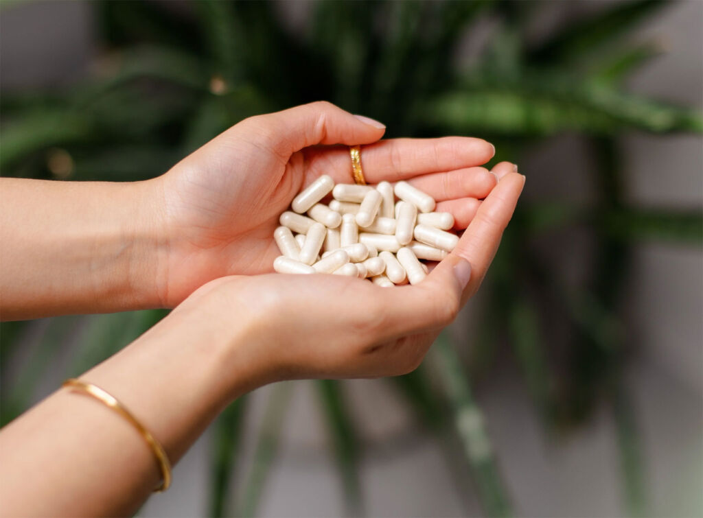 A woman holding supplement capsules in her cupped hands