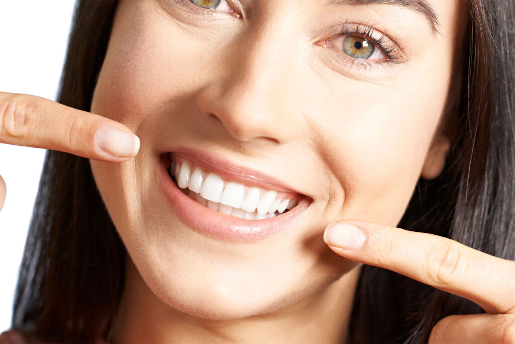 A woman pointing to her perfect teeth