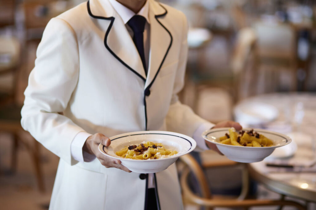 A member of the restaurant team bringing dishes to a table