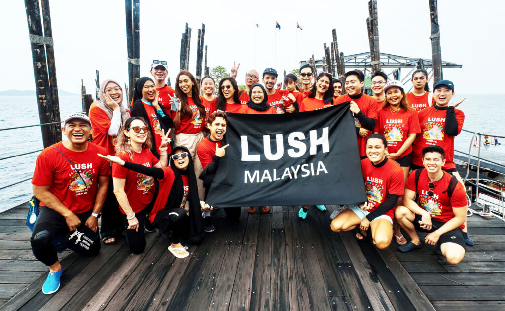 Participants on the trip holding up a Lush Banner on a jetty