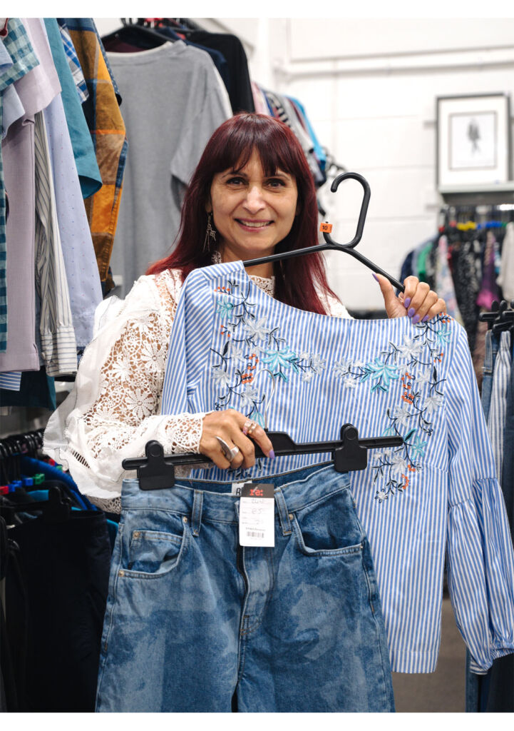 Rebekah holding some fashion garments inside one of charity shops